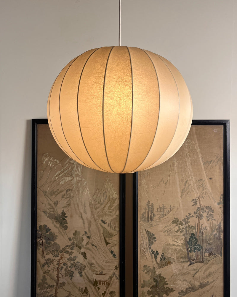 Large Italian cocoon pendant light with warm glow over artwork