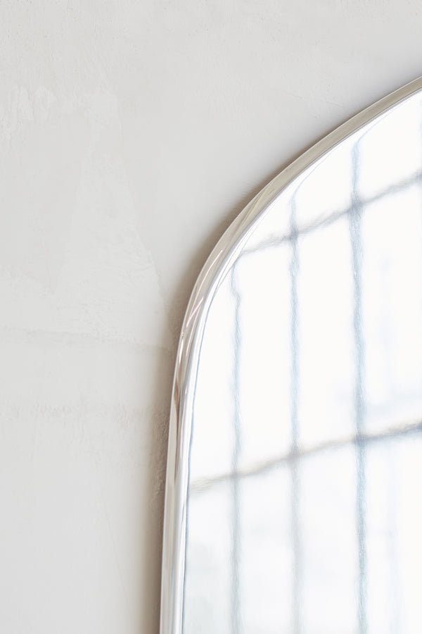 Geo Mirror in Polished Aluminum — side angle showing reflective surface and curved edge