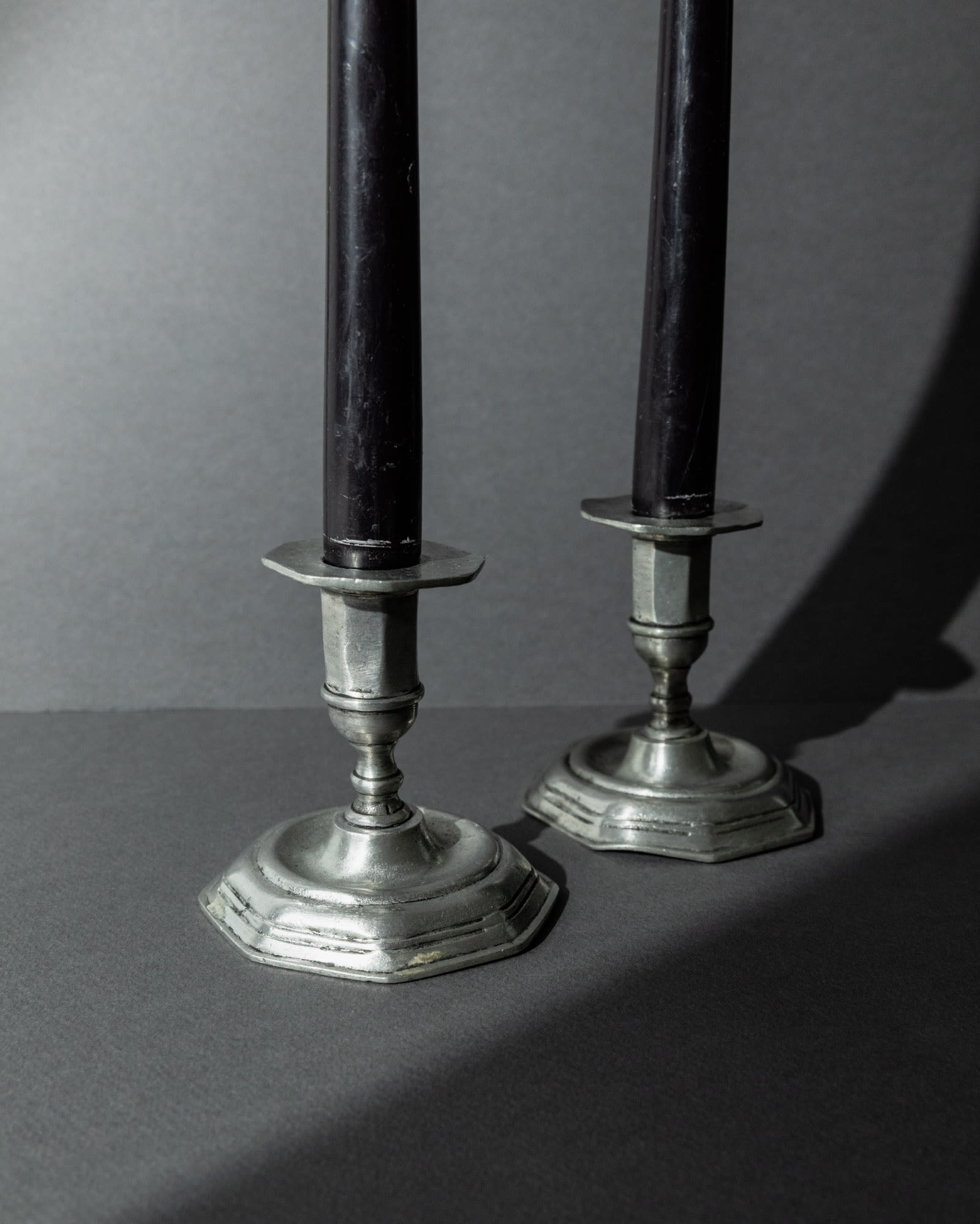 1900s Pewter Candleholders Set of 2 — angled view on dark background