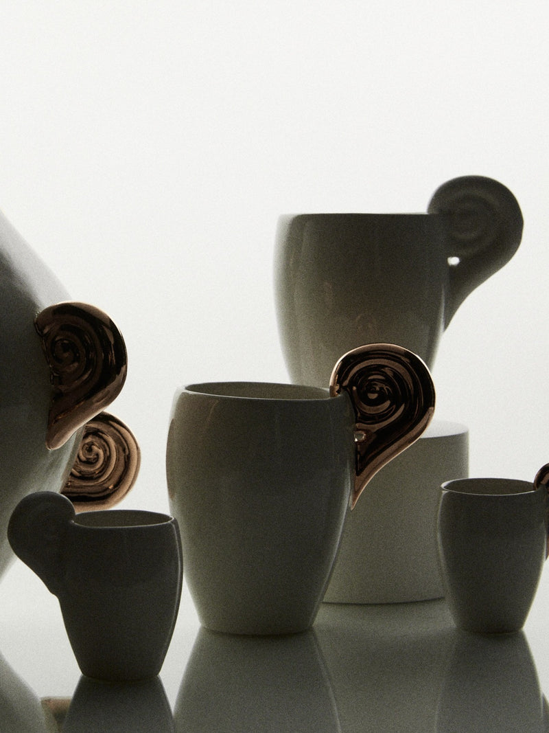 White ceramic cups with sculptural spiral handles detail view