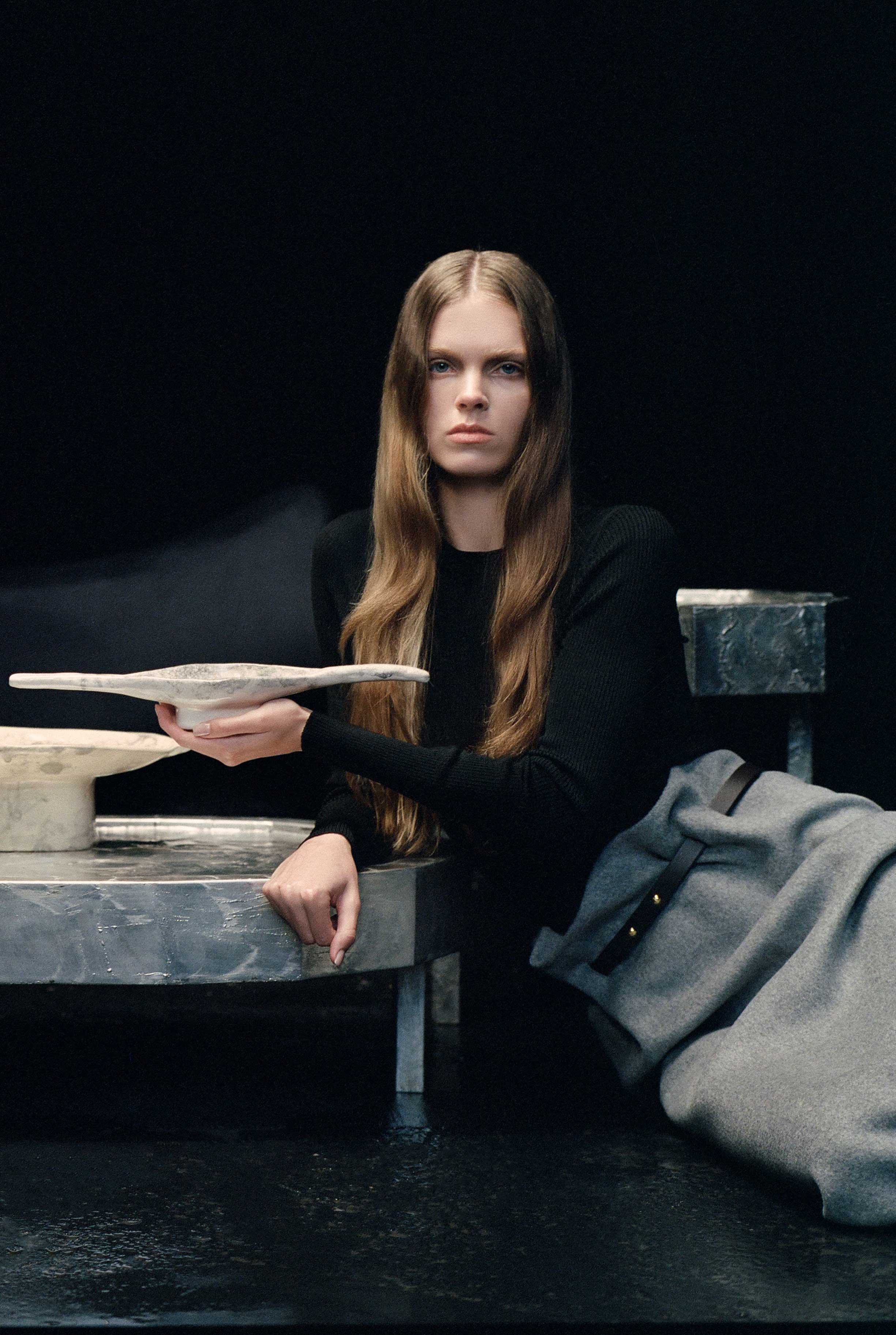 Splav Tin Table (bigger) — model seated beside metallic table in dark setting