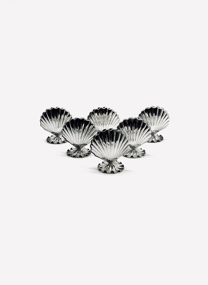 Six vintage silver shell-shaped card holders arranged in decorative formation