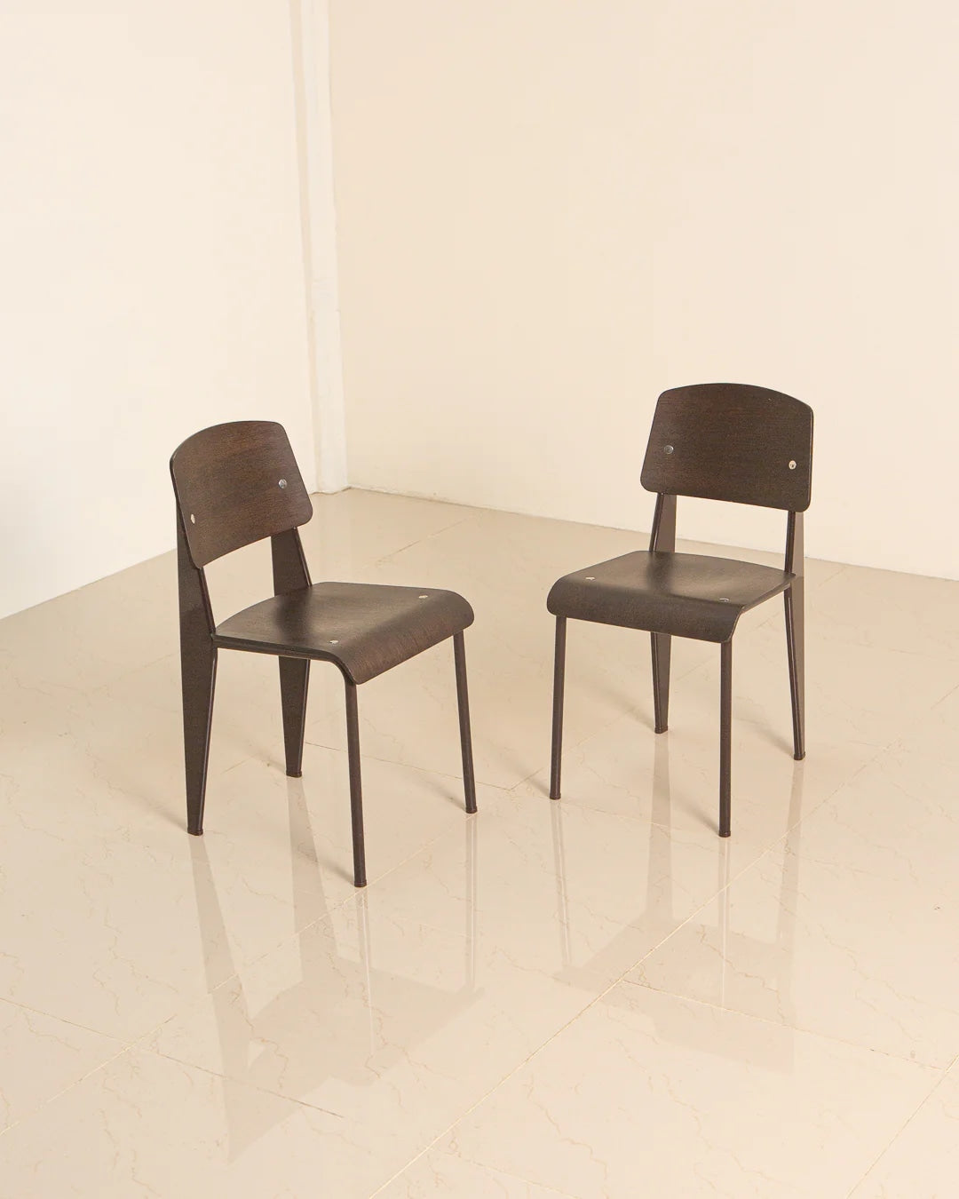 Two dark brown Standard chairs by Jean Prouvé in minimalist corner