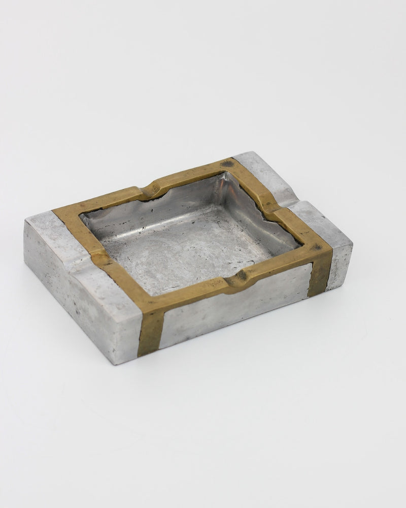 Brutalist Ashtray — close-up of metal surface with brass accents