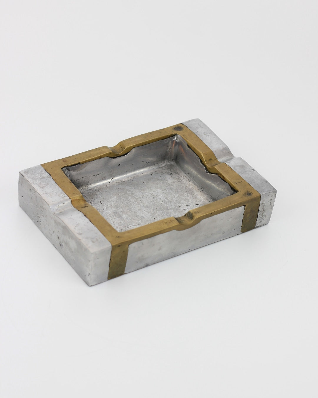 Brutalist Ashtray — close-up of metal surface with brass accents