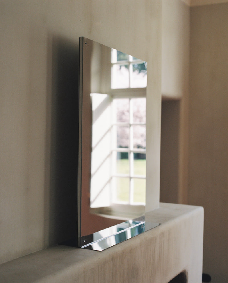 Large rectangular flat mirror with chrome frame on wooden surface