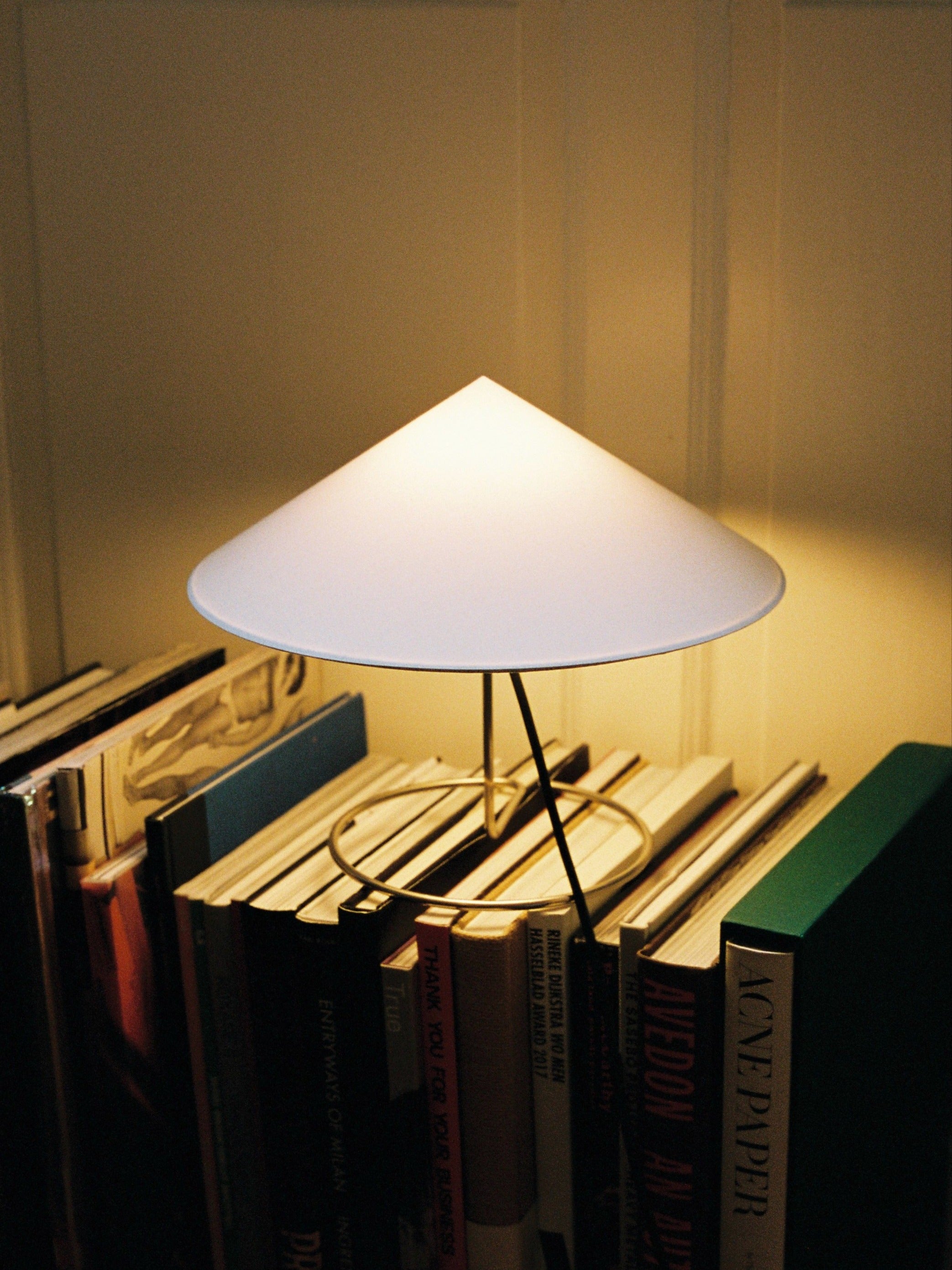Douli Table Lamp — white conical shade above stacked books