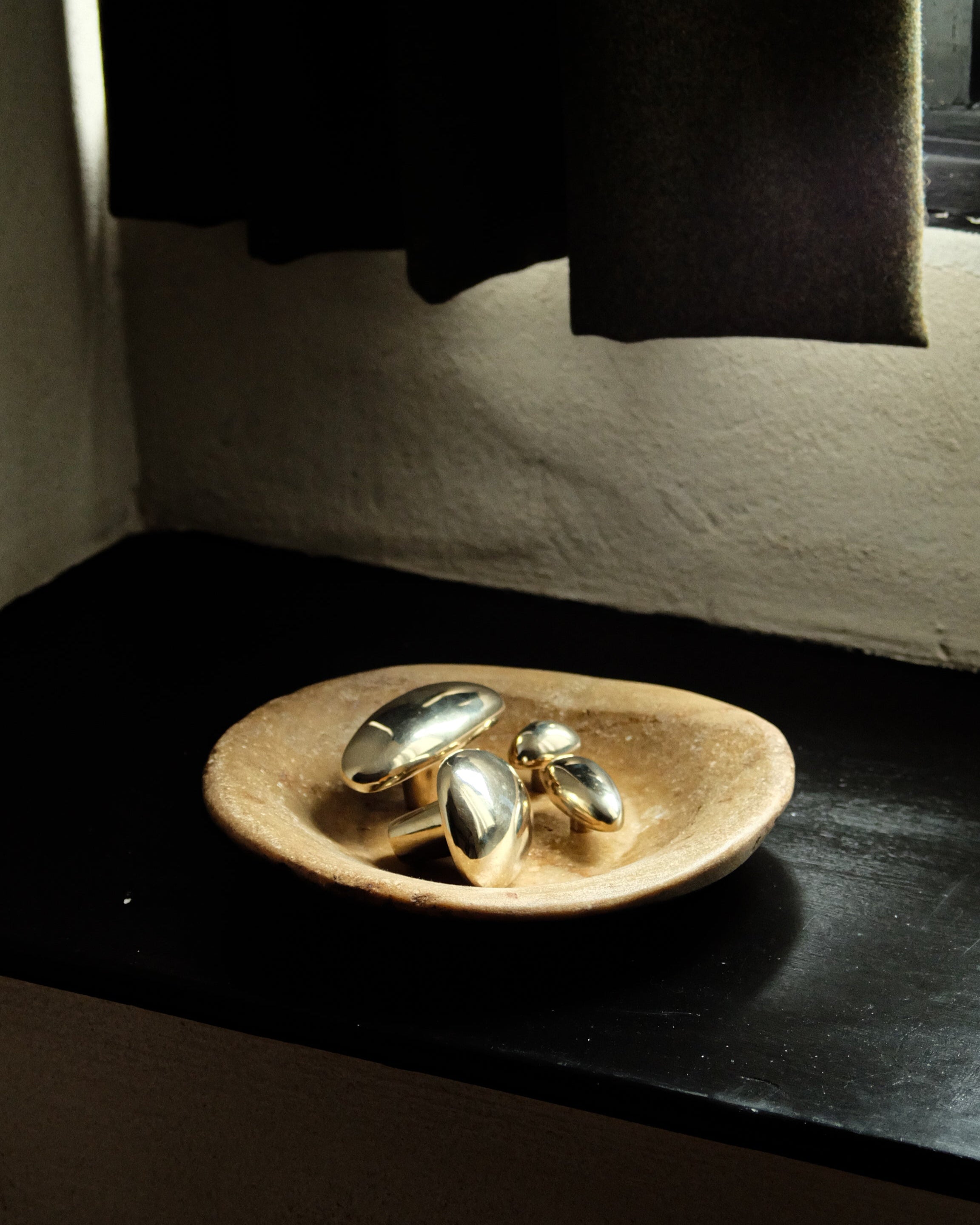 MOMI Knob/Hook Long — side angle on textured stone dish