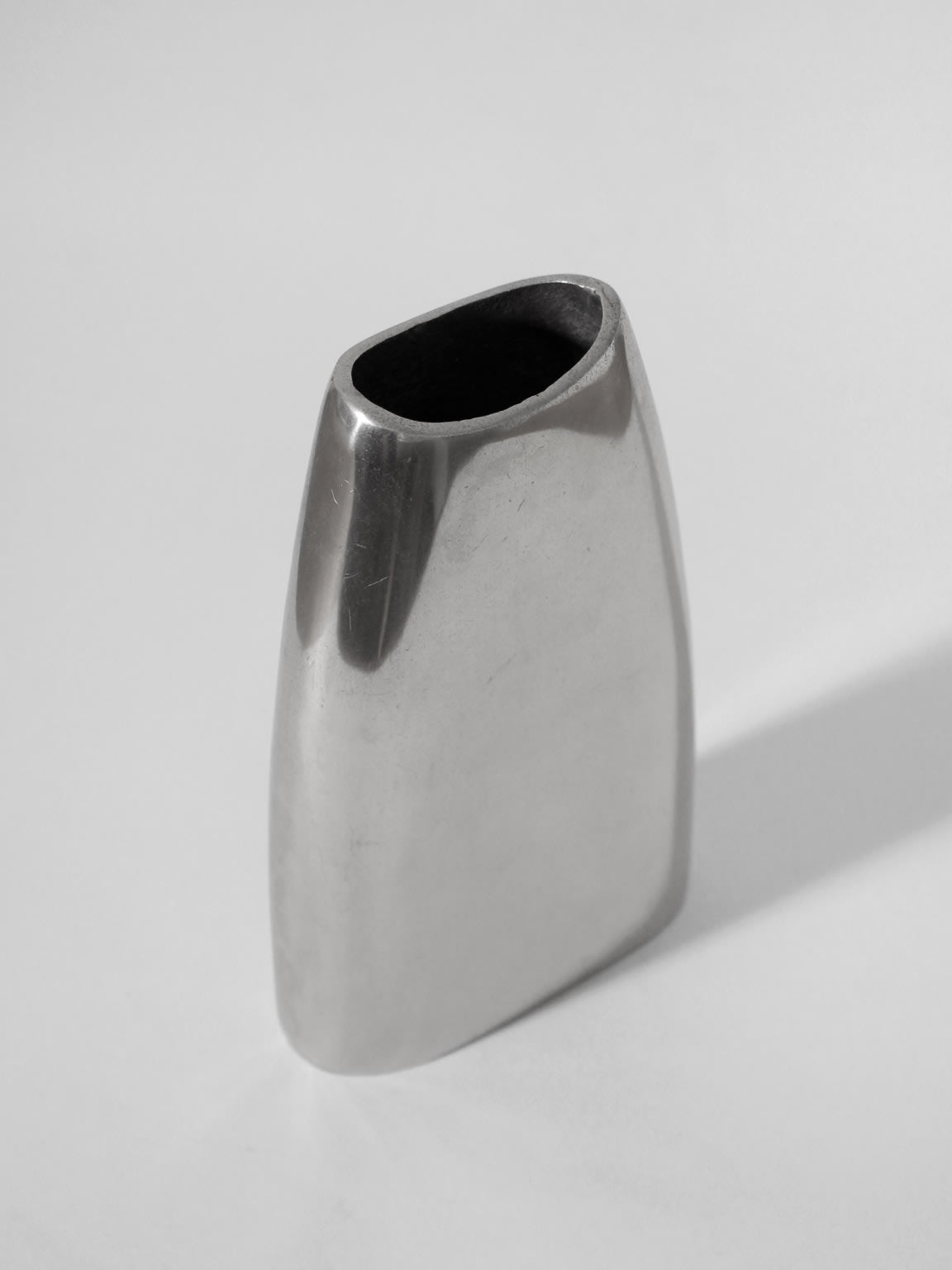 The Polished Aluminum Flat Tall Vase by Vintage Stories is a sleek, modern silver vase with a rounded rectangular shape and open top, crafted from aluminum and shown against a plain white background.