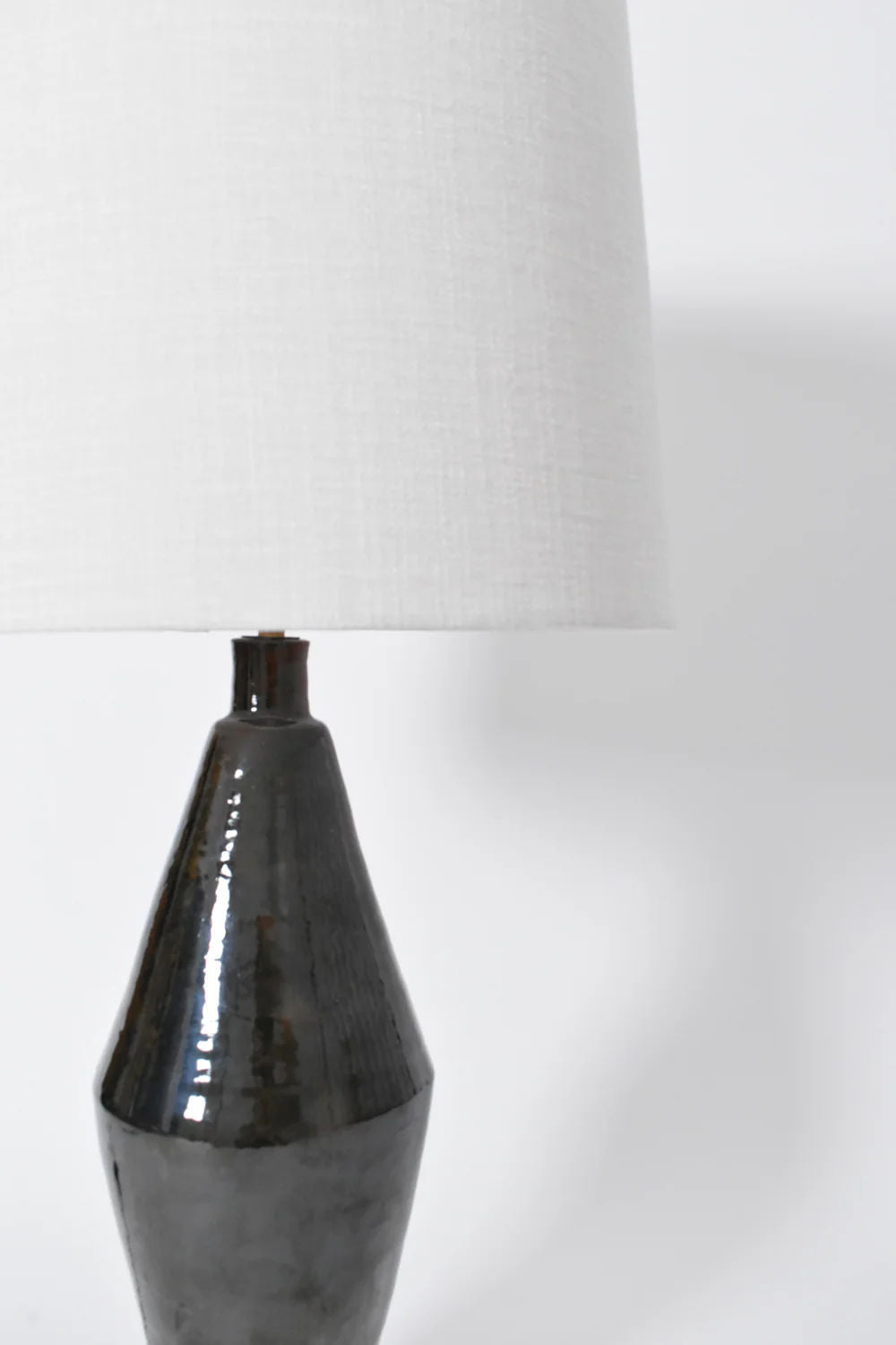 A close-up of the "Arrabida" Green Table Lamp by Barracuda Interiors, featuring a glossy green ceramic base and a white fabric lampshade, made in Portugal, set against a plain white background.