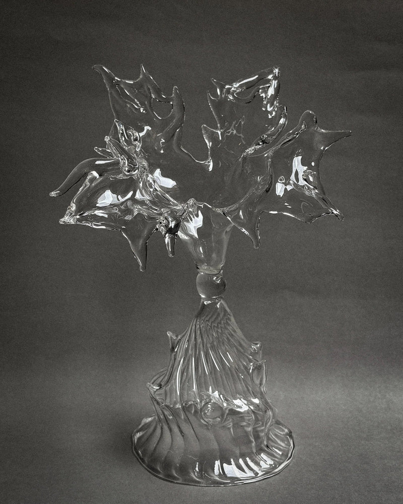 Clear glass sculpture with flowing organic forms on ribbed pedestal base