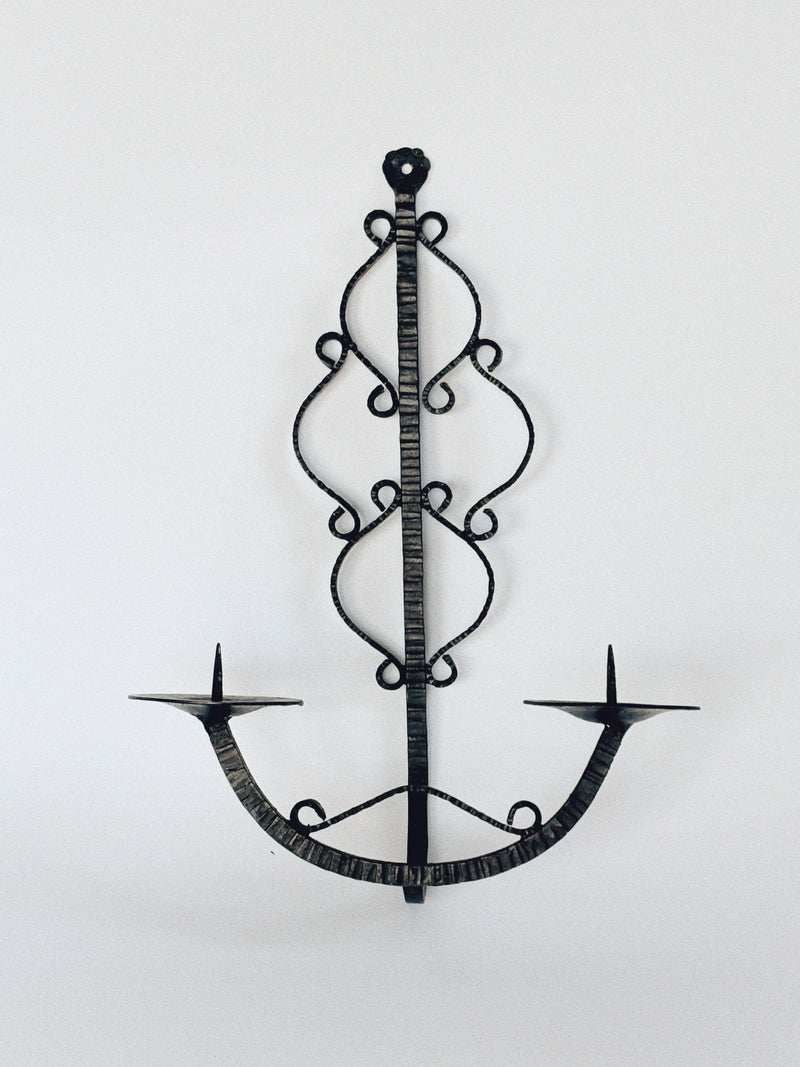 The Huerto Metalwork Wall Candleholder from Poland is a vintage-style wrought iron sconce with two arms and intricate swirled details, shown on a plain white background.