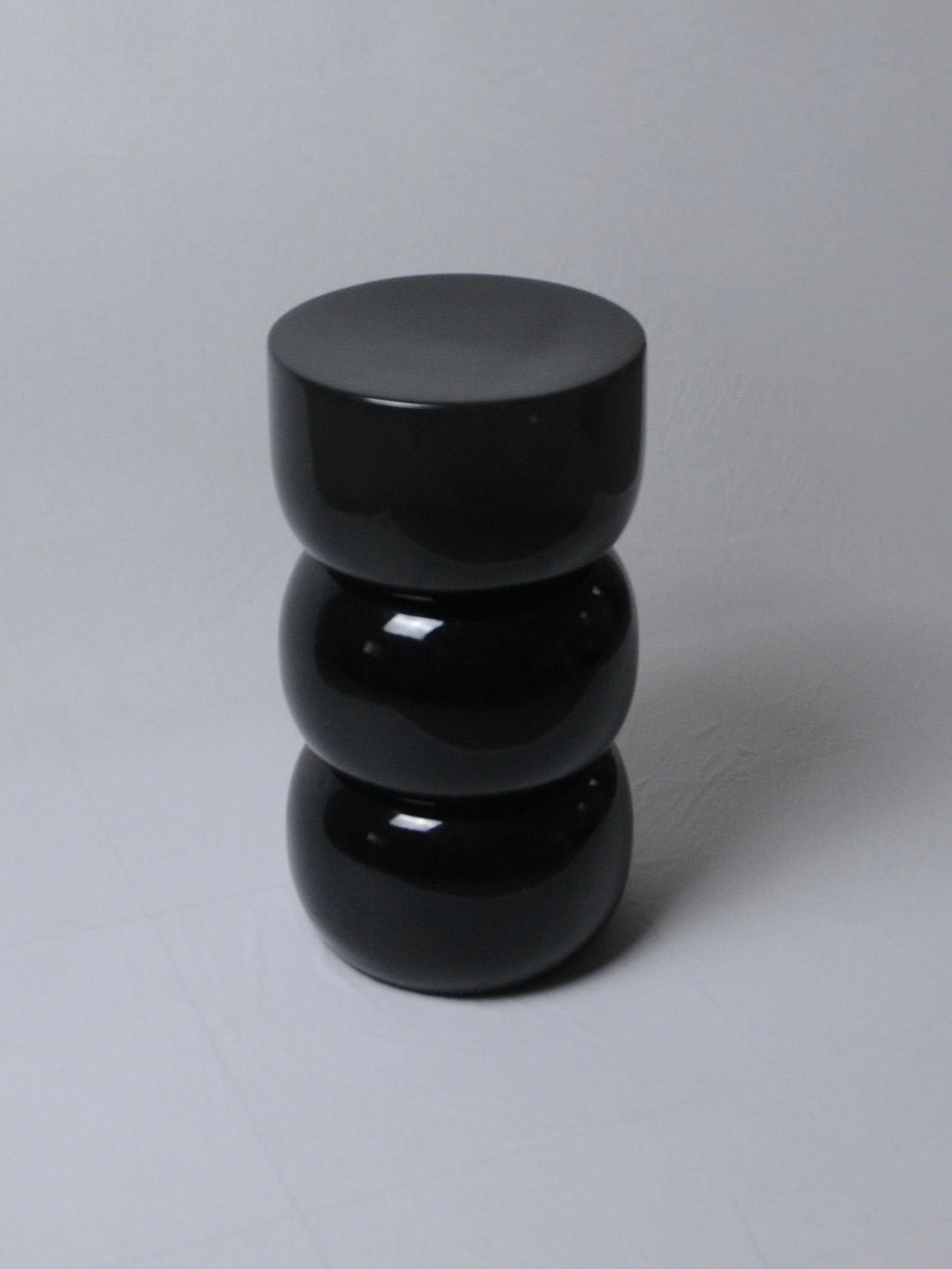 Chess' Stool convex in lacquer wood — side angle showing glossy black finish