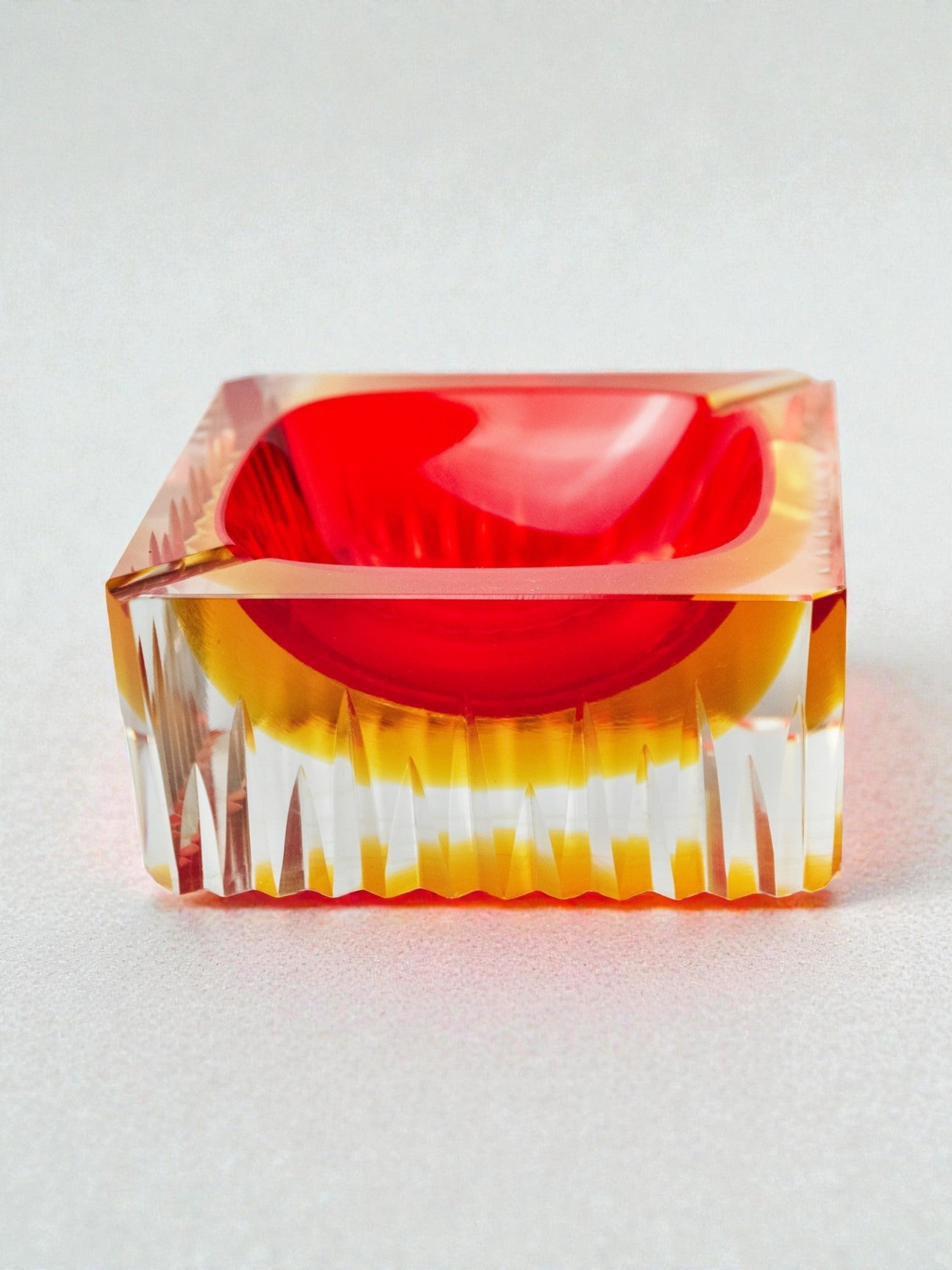 Red and yellow cubic Sommerso ashtray by Seguso, Murano, Italy, 1970 — angled view on textured surface