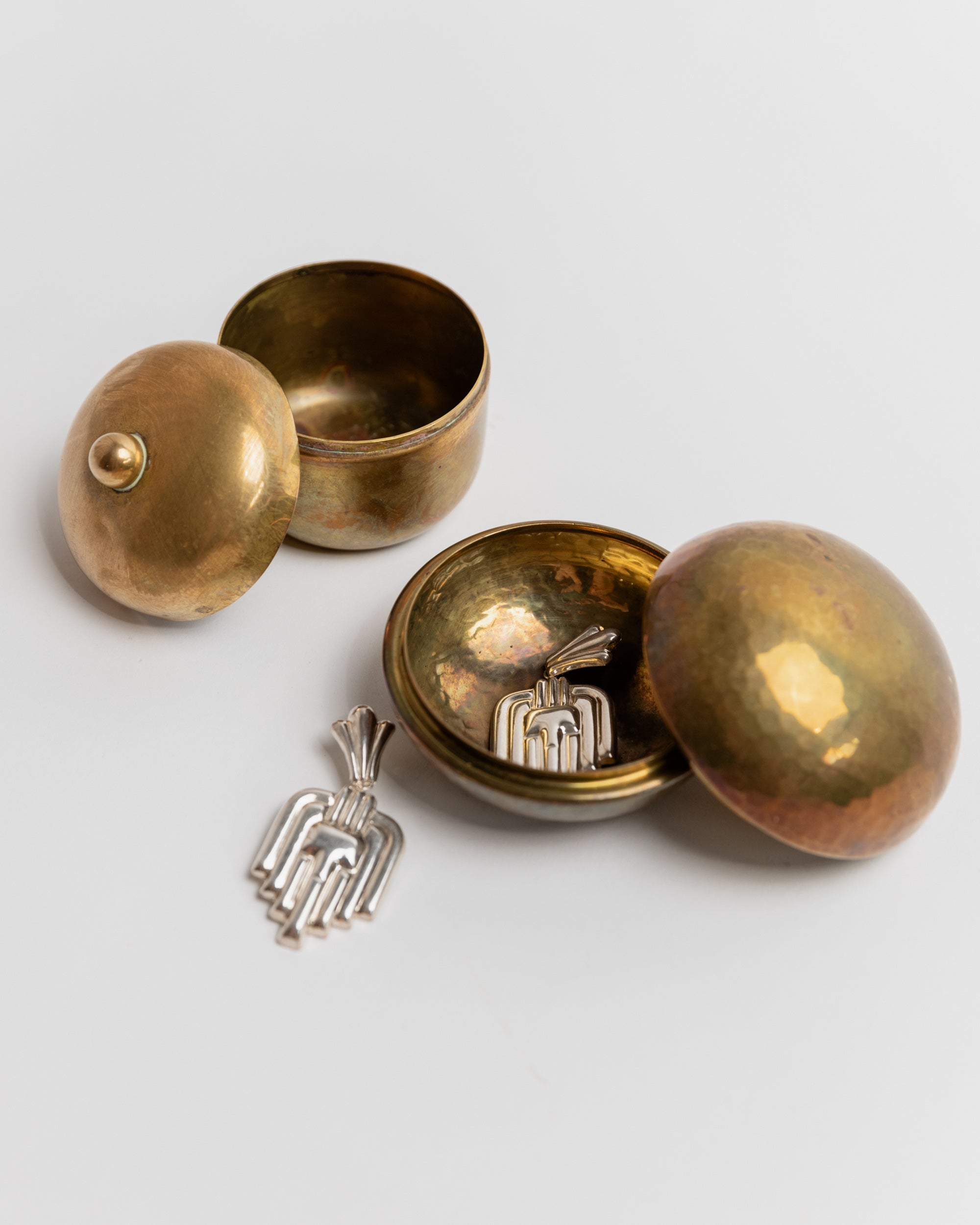 Vintage brass tins opened displaying silver decorative items inside