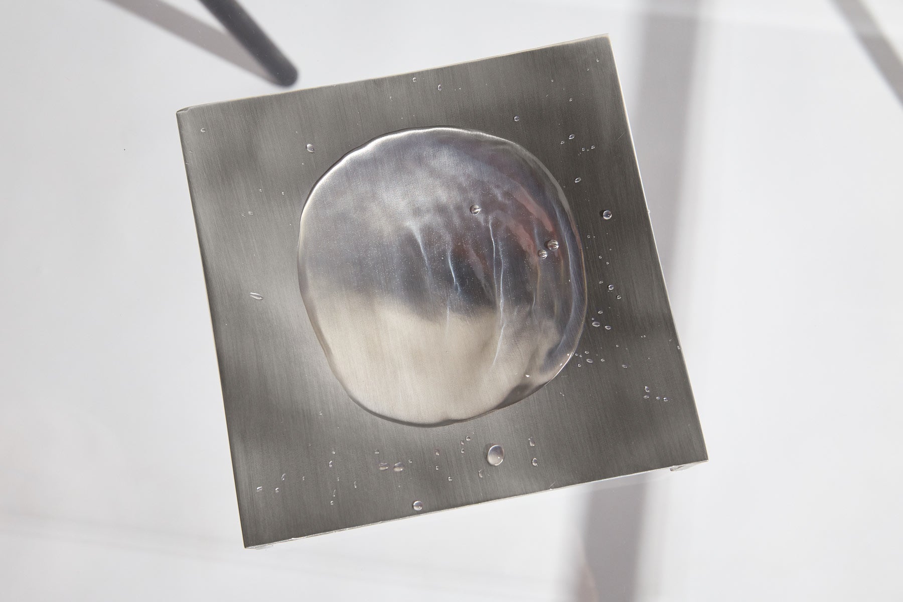The LESORR Square Aluminum Vide-Poche is shown from above, its large round water droplet reflecting light and smaller droplets nearby—a stylish aluminum catchall for your small essentials.
