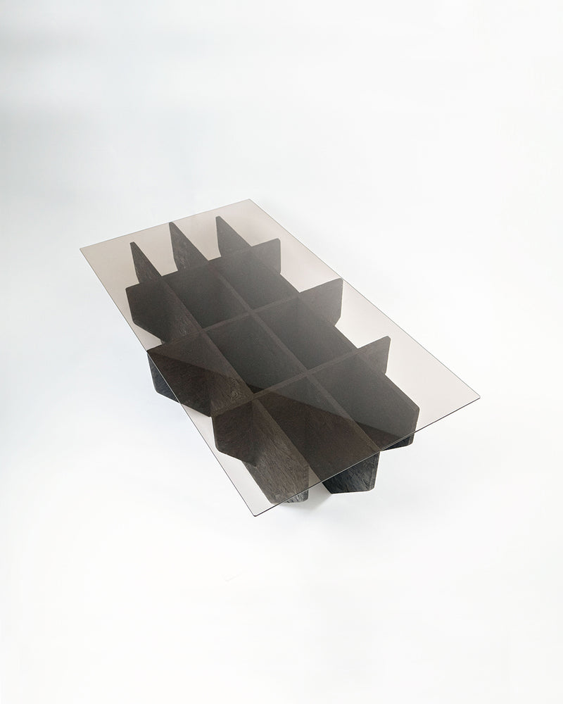Coal coffee table with sculptural dark wood base and glass top