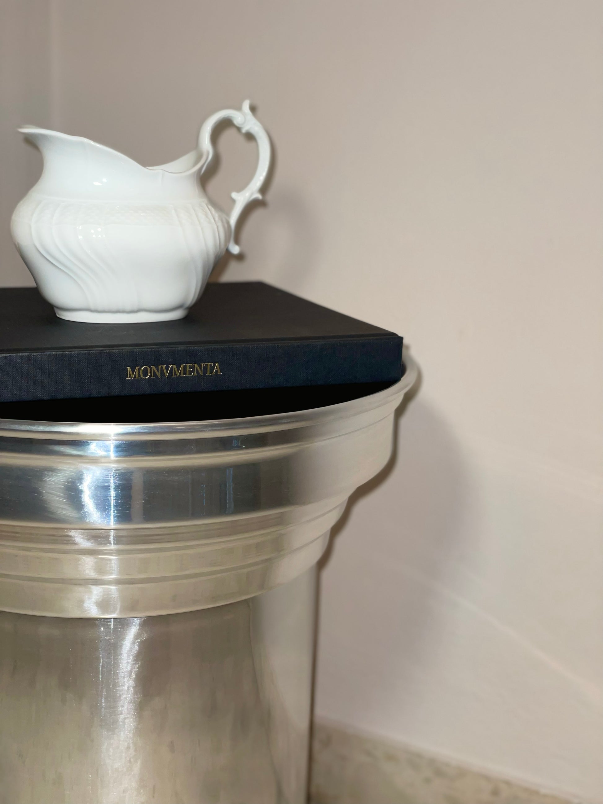 Art Deco Side Table - Mirror-Polished Metal Collection — close-up with white ceramic pitcher and book