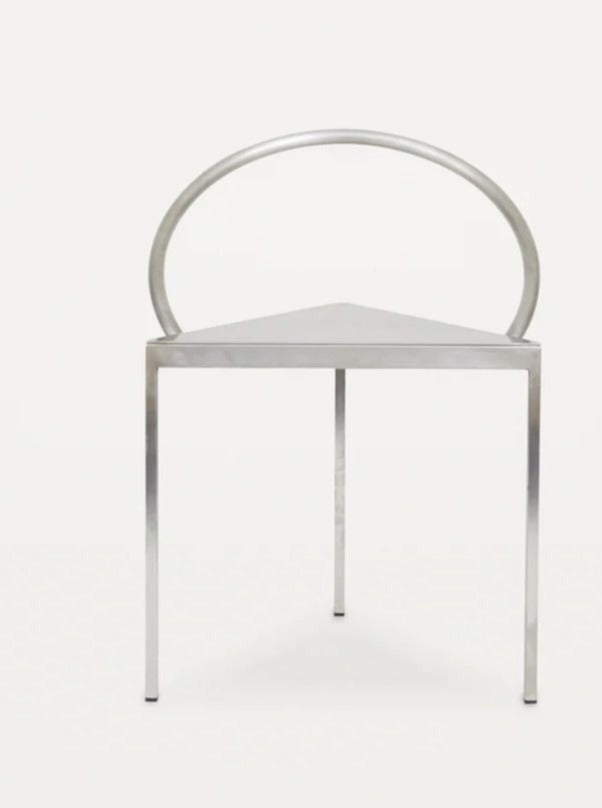 A sleek, minimalist stainless steel chair with a triangular seat and a half-circle backrest. The Triangolo Chair | Stainless Steel by FRAMA has four straight legs and a modern, industrial aesthetic, set against a plain white background.