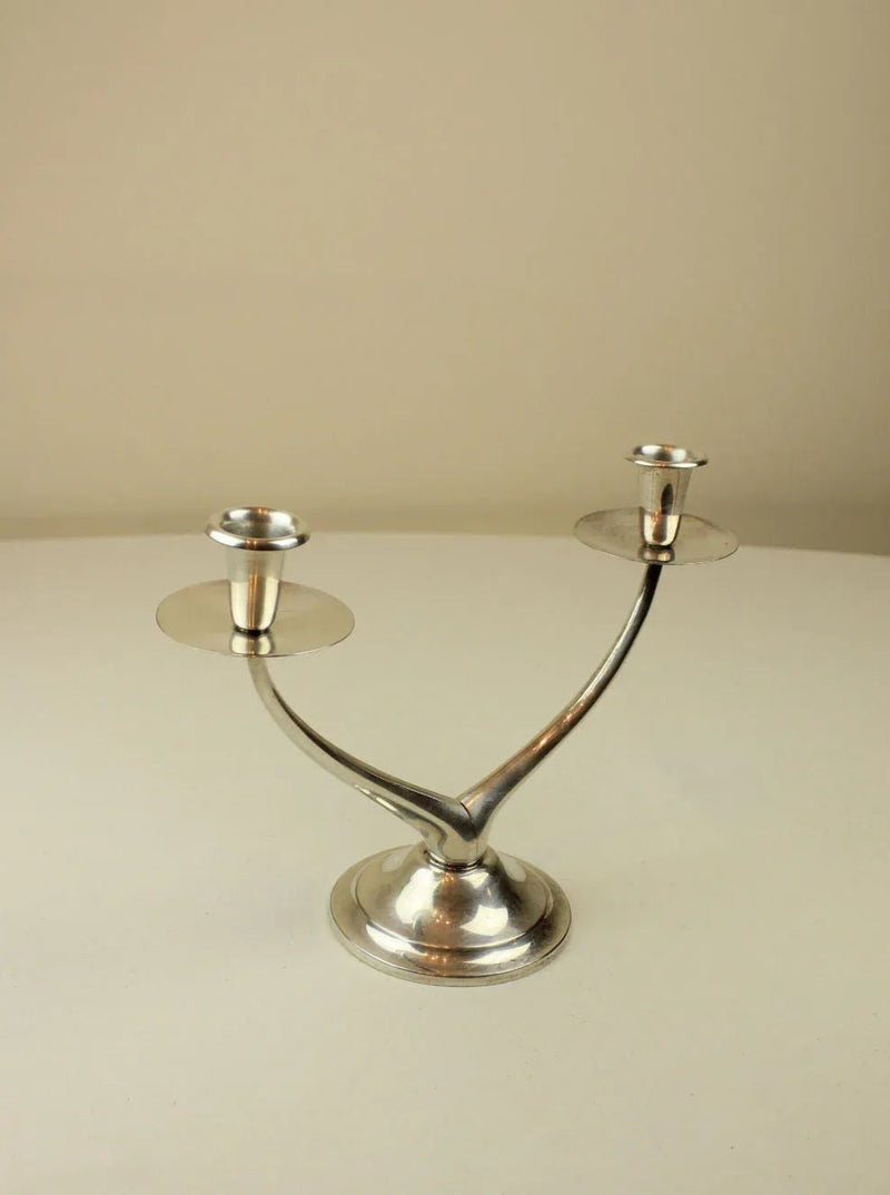 Modern black metal wishbone candleholder with brass accents on white background