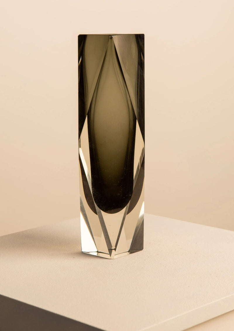 A tall, reflective Vase by Flavio Poli for V. Nason & Co prism with a multifaceted surface, casting subtle shadows on a light beige background.