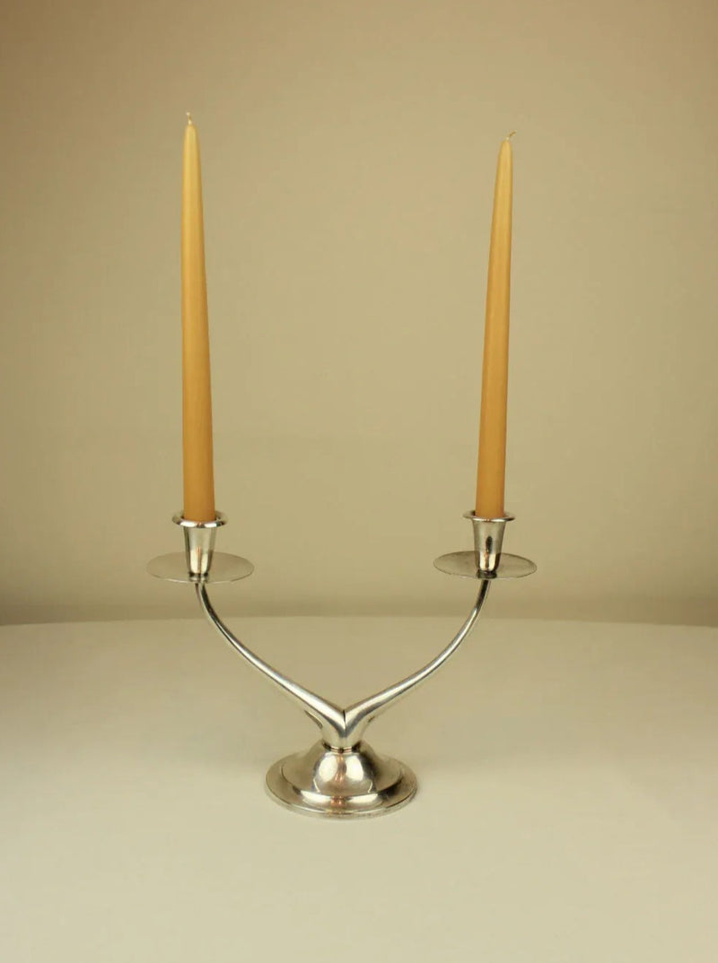  Close-up of wishbone candleholder with two white taper candles lit
