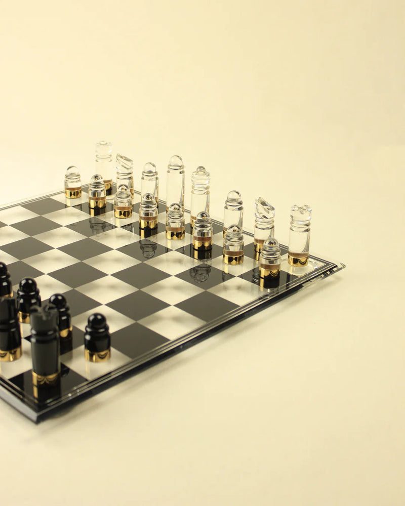 An acrylic Boga Avante Shop Chess & Checker Board set on a checkerboard, with clear and frosted pieces arranged for a game, on a neutral light background.