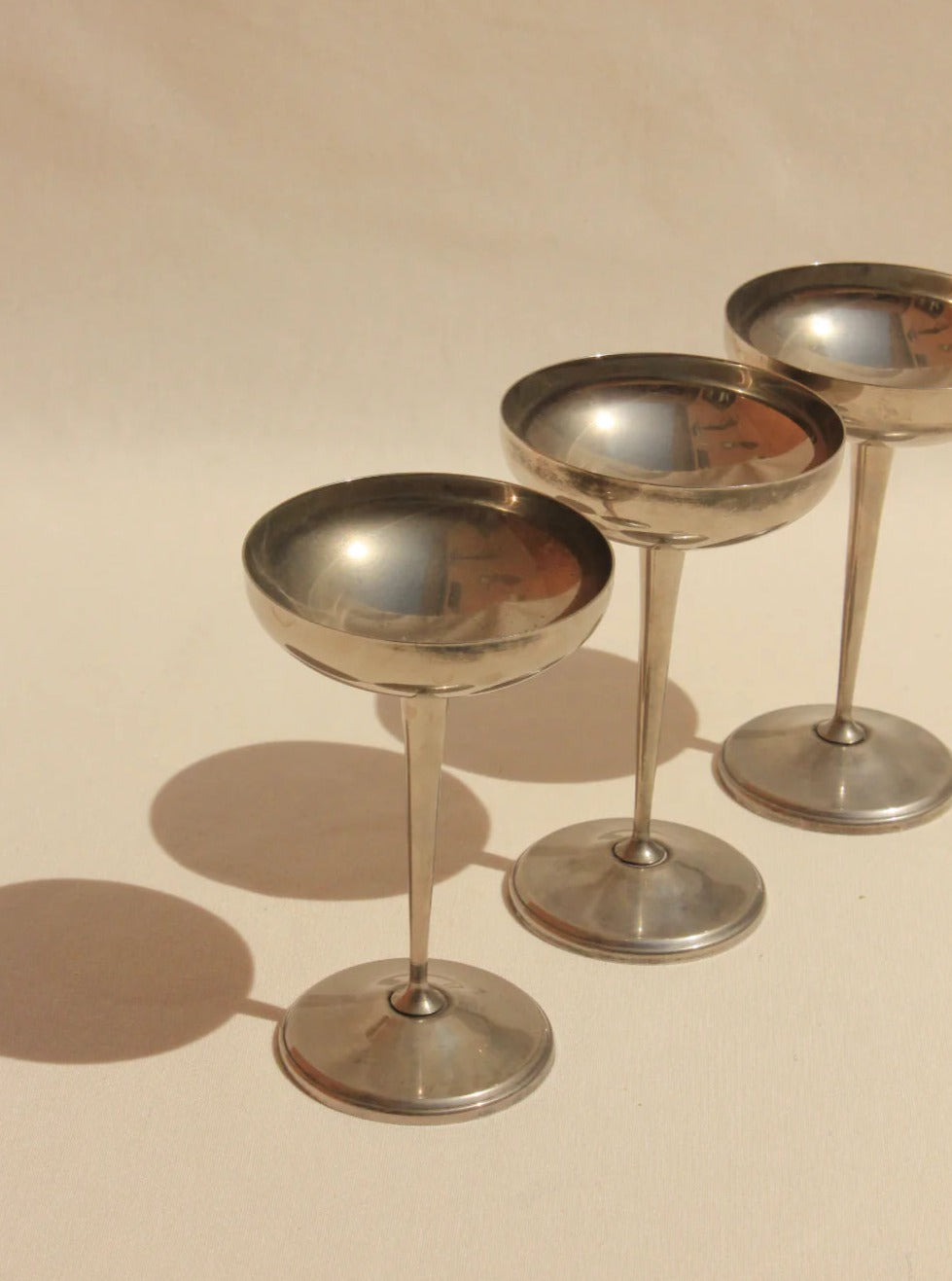 Three vintage Boga Avante Shop Alpaca Silver goblets with long stems and circular bases, arranged in a triangular formation on a beige background with soft lighting.