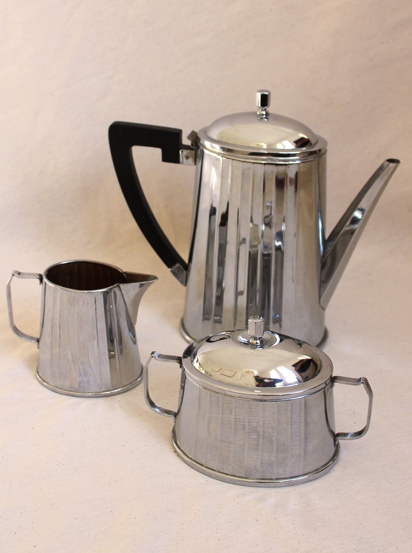 A shiny Maison Collectible Art Deco Coffee Set on a neutral background, featuring a tall percolator with a black handle, a small creamer, and a sugar bowl with lid.