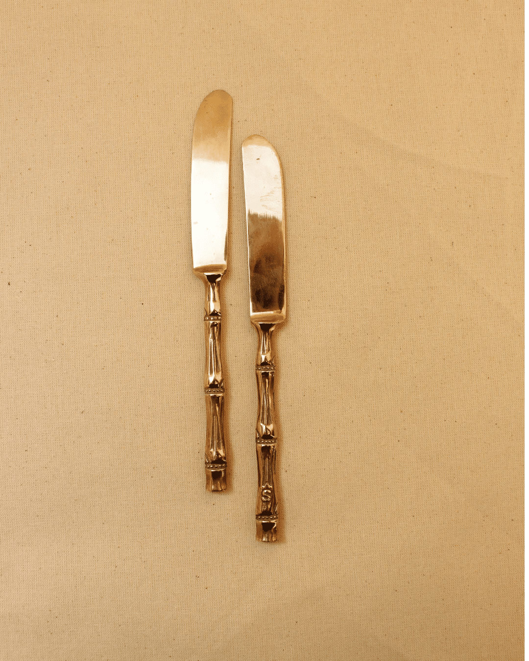 Two Boga Avante Shop vintage silver butter knives with ornate handles laid on a table setting background.