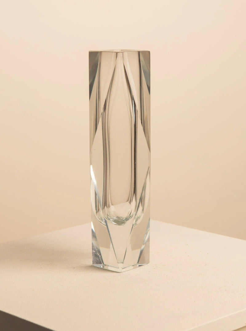 The Transparent Vase by Flavio Poli for Seguso, from Treaptyque, stands tall with an angular geometric design on a light-textured surface against a neutral beige background, enhancing the luxury interior vibe with its sculptural form.
