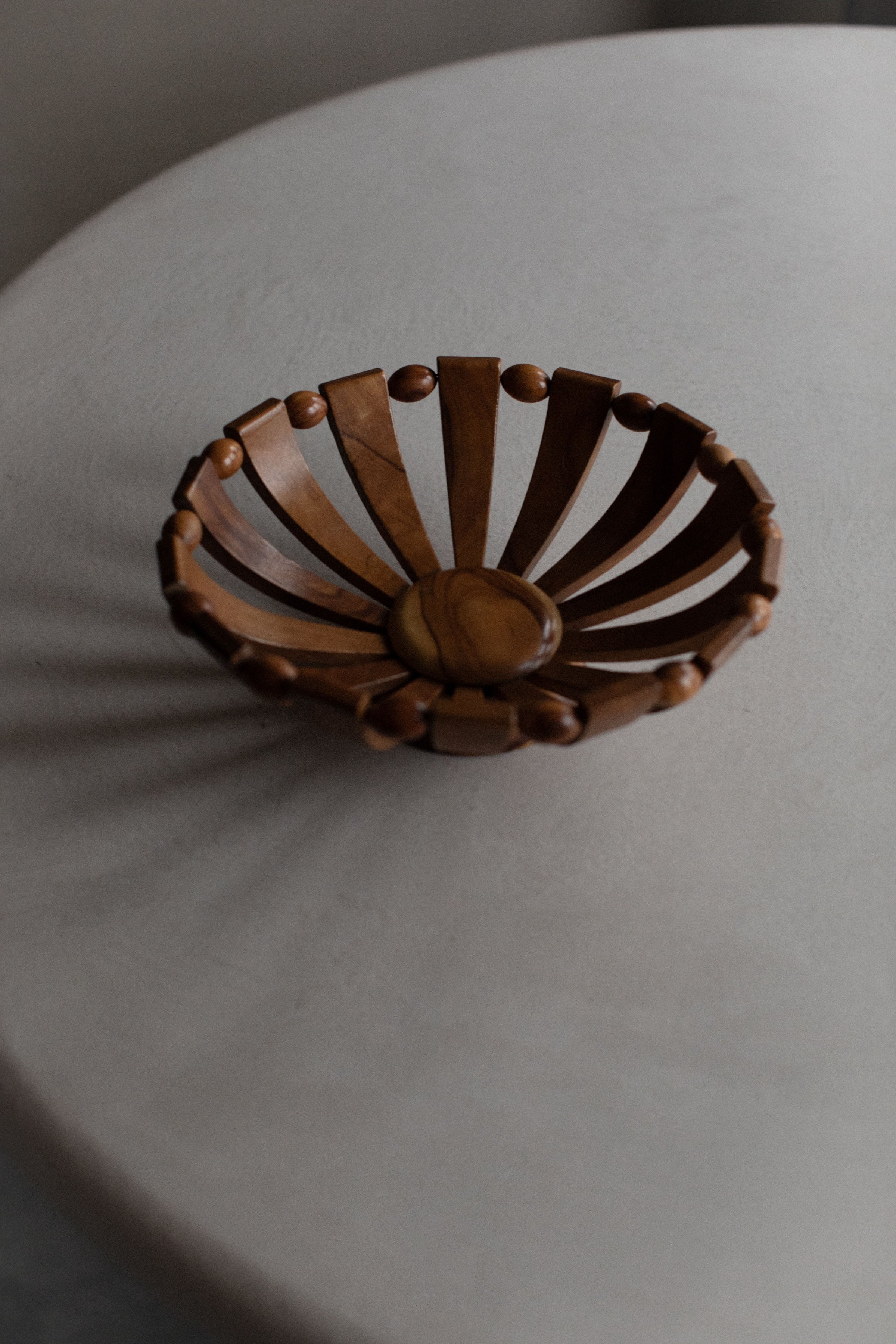 A 1950's Art Deco Bowl by Out For Lunch with a natural grain and radial design placed on a gray surface, showcasing a minimalist and elegant aesthetic.