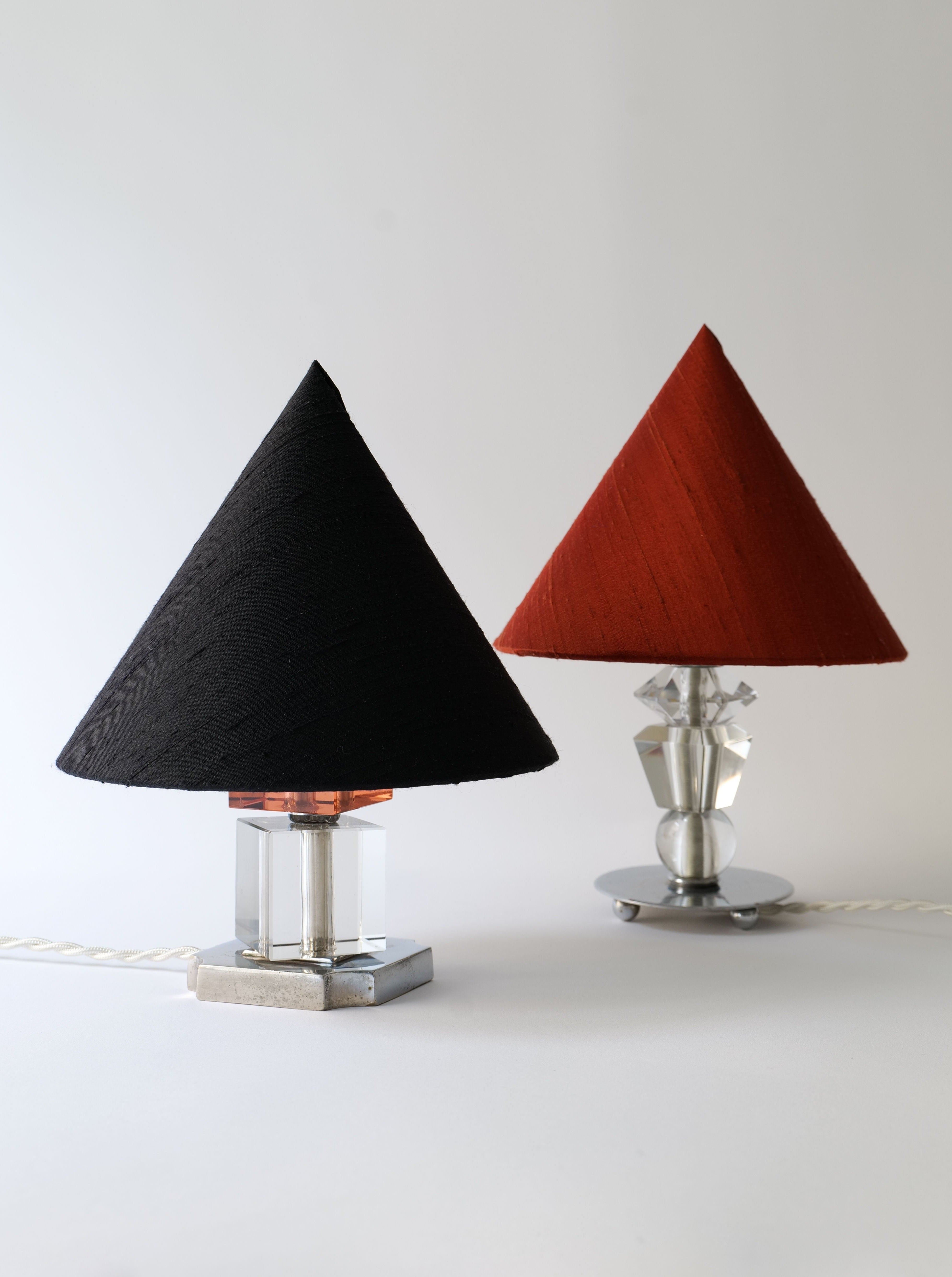 Two minimalist Collection apart Deco Table Lamps with geometric lampshades, one black and one red, set against a neutral background.