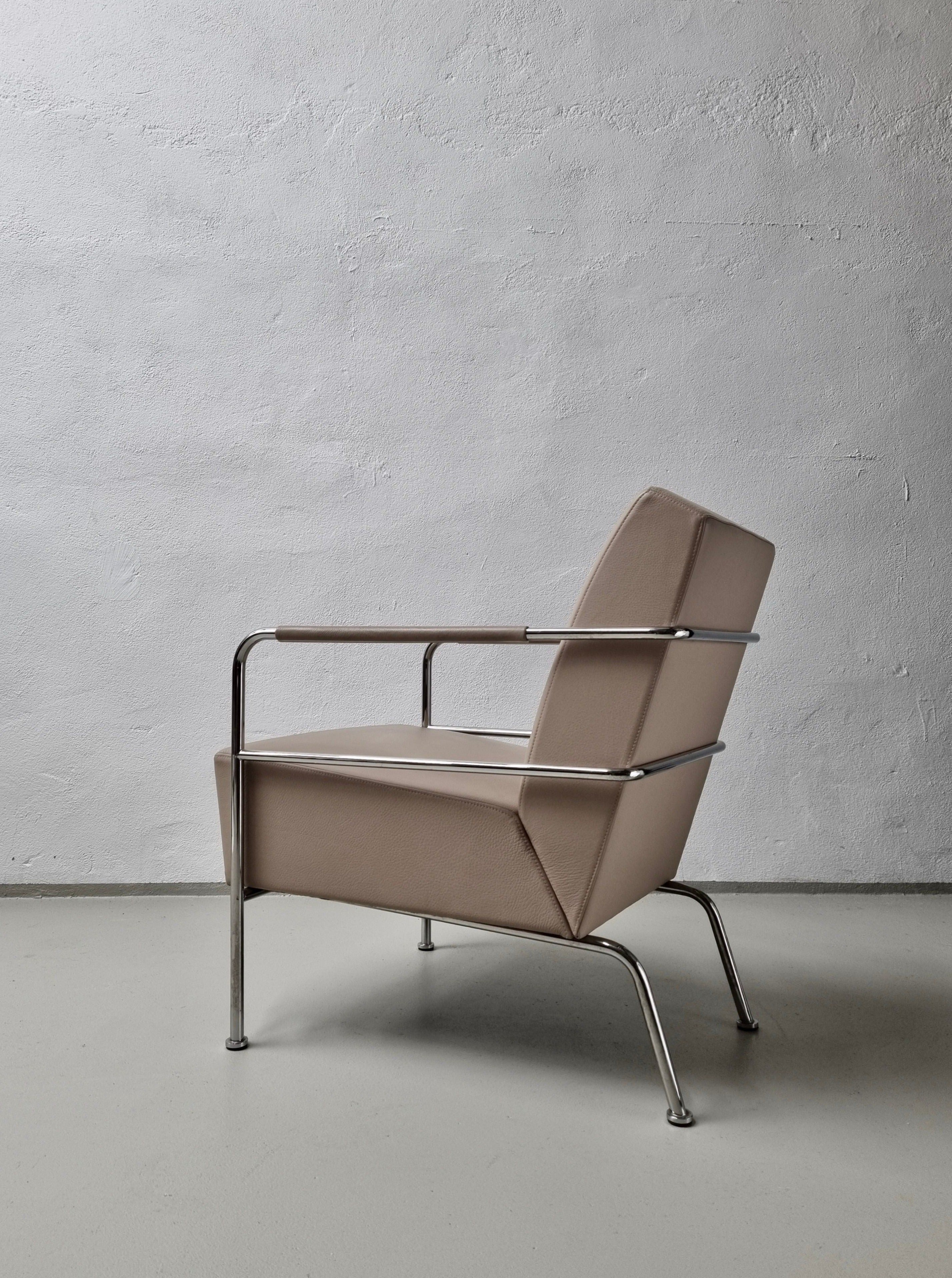 A modern Chairs by Gunilla Allard for Lammhults 1990s with a high-quality leather cushion and a shiny chrome frame, positioned against a textured gray concrete wall in a minimalist setting.