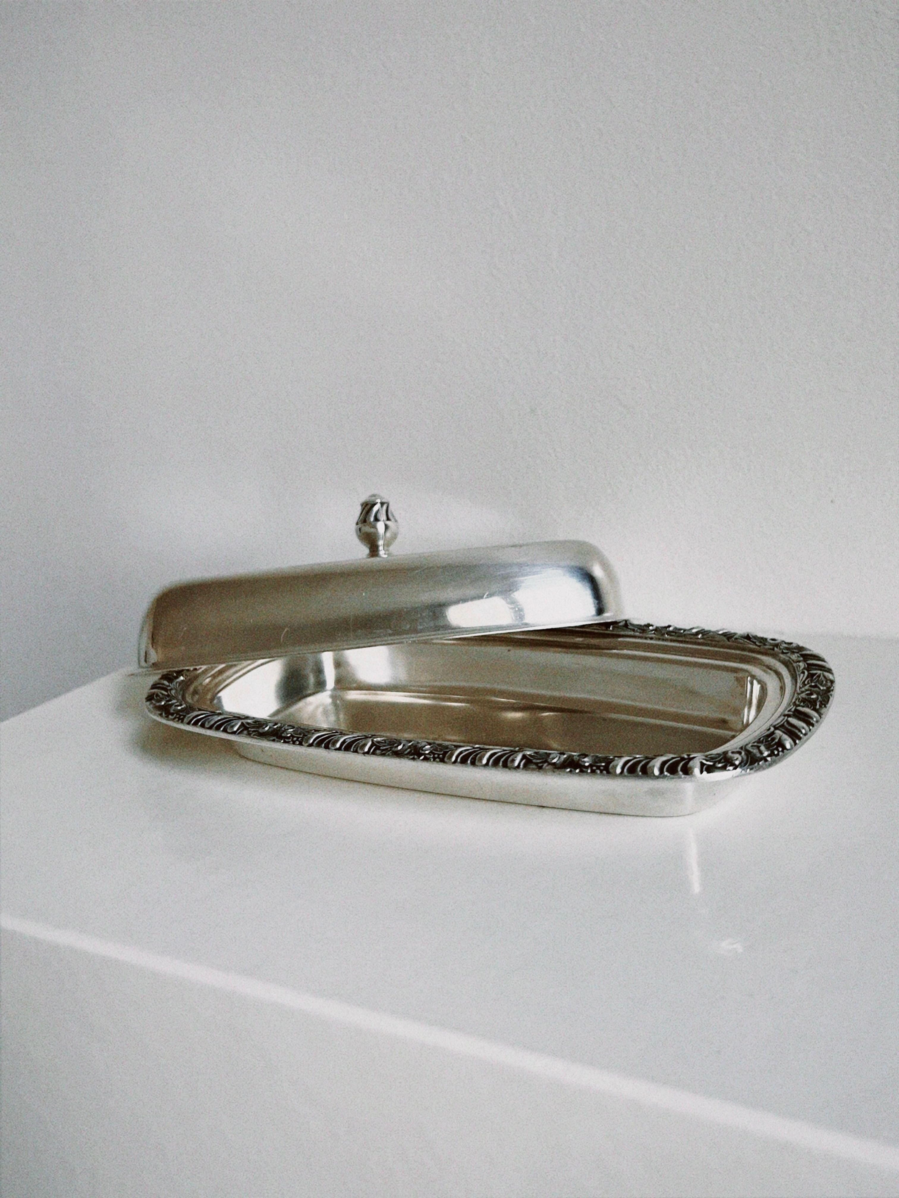 A luxurious silver ornate butter dish with intricate designs and detailing