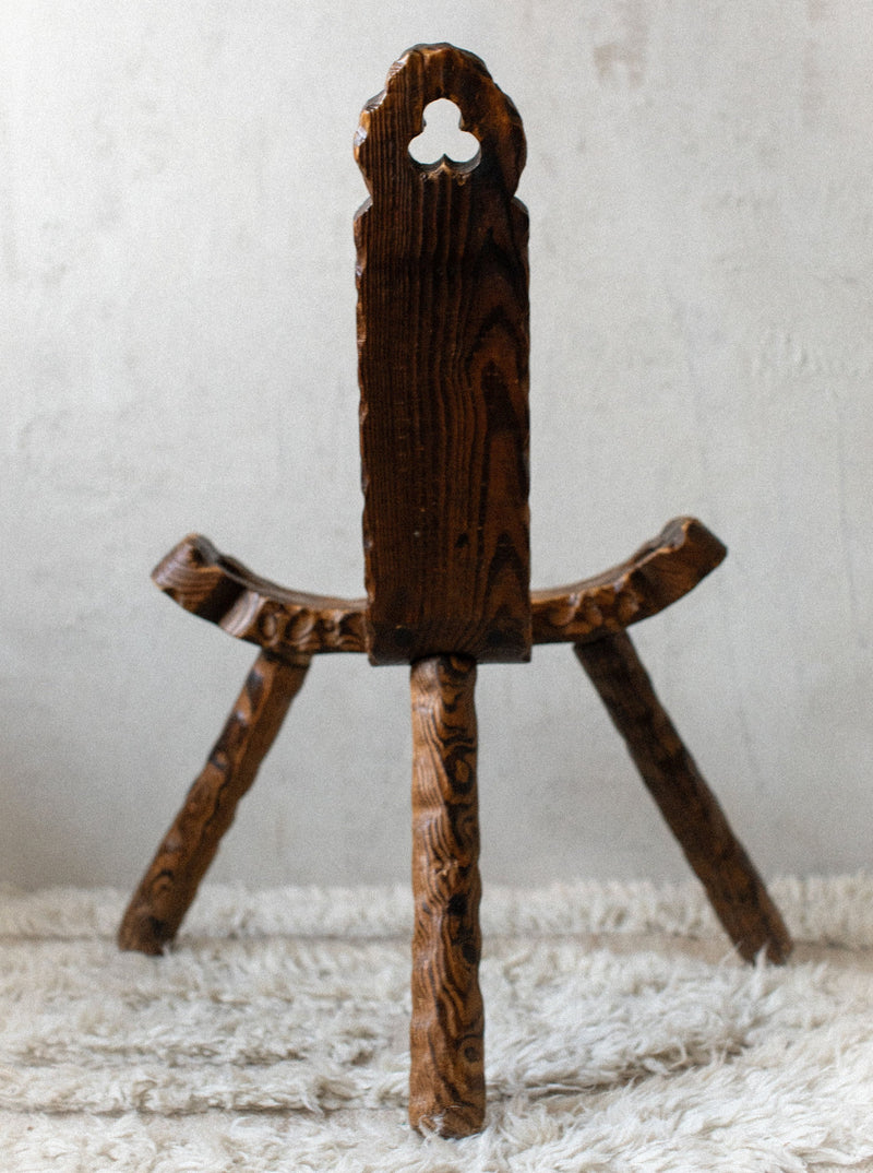 A rustic brown wood Out For Lunch children's rocking horse placed on a shaggy white rug, with intricate carvings and a traditional keyhole design in the saddle area.