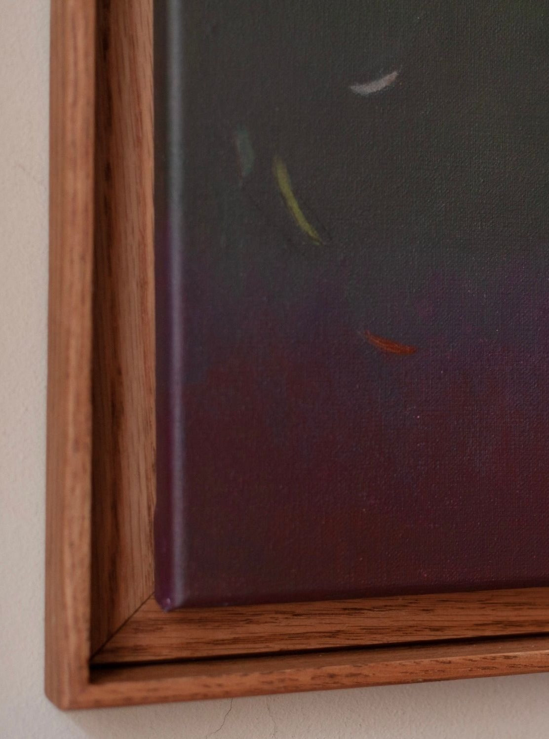 A close-up of the framed painting "Ponds and Breezes #8, 2023" by Rebecca von Matérn reveals a contemporary design with a dark gradient and scattered white, yellow, and red brush strokes. The wooden frame's simple yet sophisticated natural finish enhances any luxury interior.