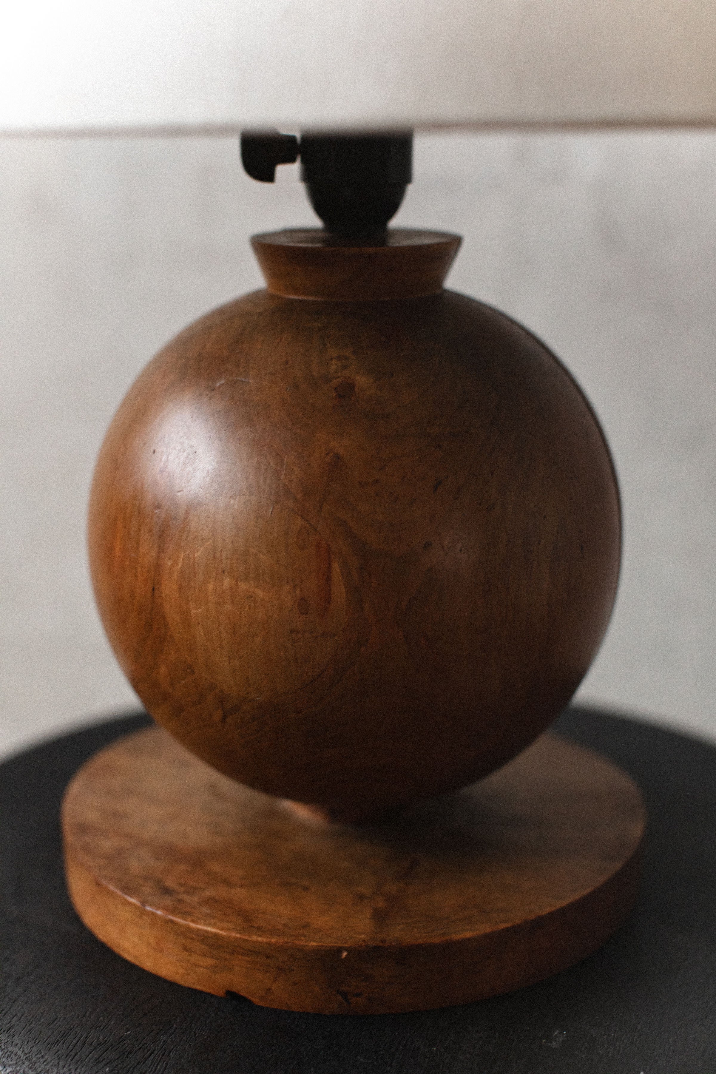 A close-up image of a round, wooden container with a smooth, glossy finish, featuring celestial motifs, placed on a circular wooden base, against a neutral background by Out For Lunch - the 1920's Art Deco Lamp.