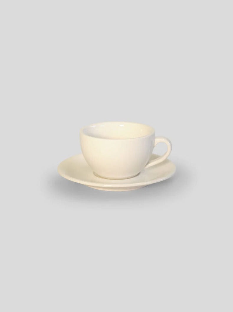 A simple white ceramic coffee cup with a saucer, The Marlow by Service Projects, displayed against a light gray background.