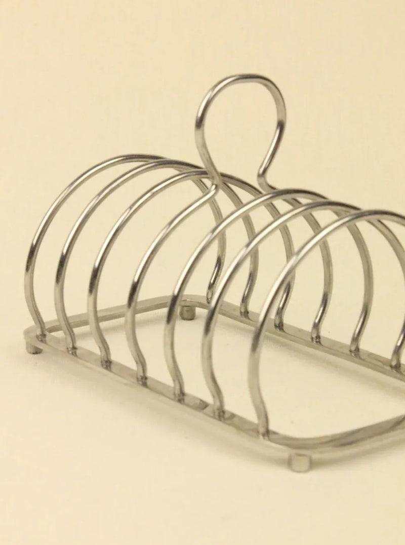 The Boga Avante Shop's Art Deco Toast Holder is a sculptural metal rack with multiple slots, featuring an elegant curved design and a back handle for easy carrying. It's an ideal piece of handcrafted collectible furniture.