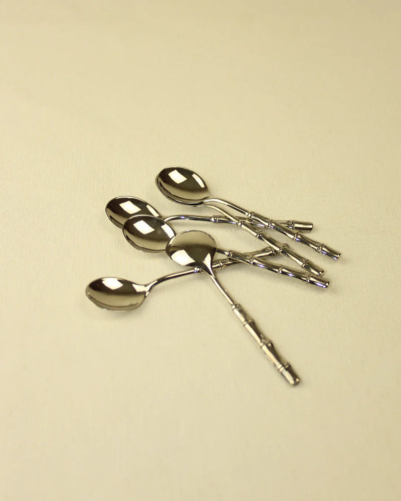 A set of four Bamboo Silver-Plated Spoons from Boga Avante Shop, with intricate handles, arranged on a light beige surface.