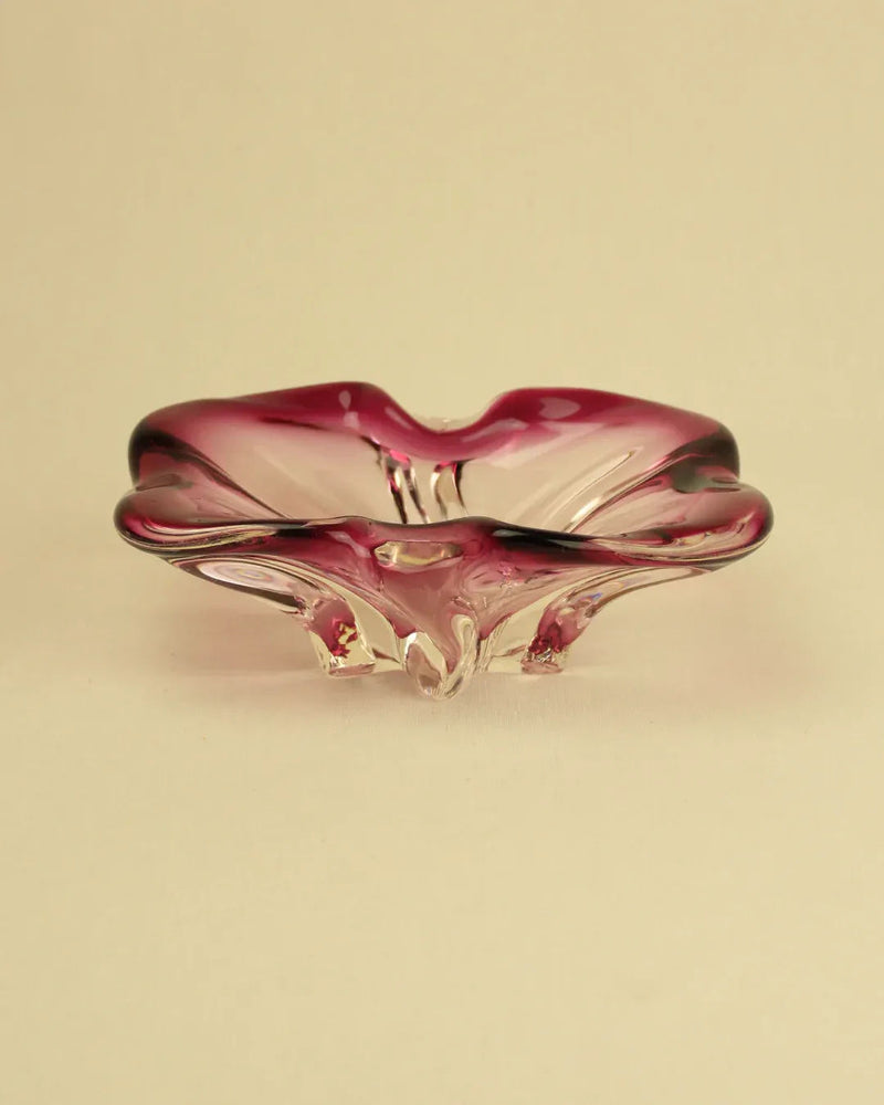 A translucent, Boga Avante Shop Murano Bowl with a wavy, organic design, displayed against a soft beige background.