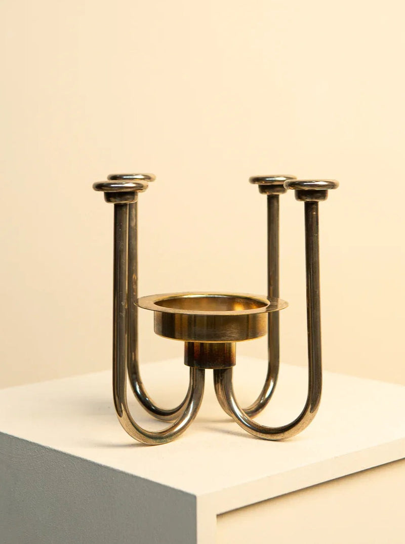 A timeless elegance Treaptyque 60's Swedish Metal Quartet Candleholder with three curved arms, each supporting a flat, round tray for candles, displayed against a beige background.