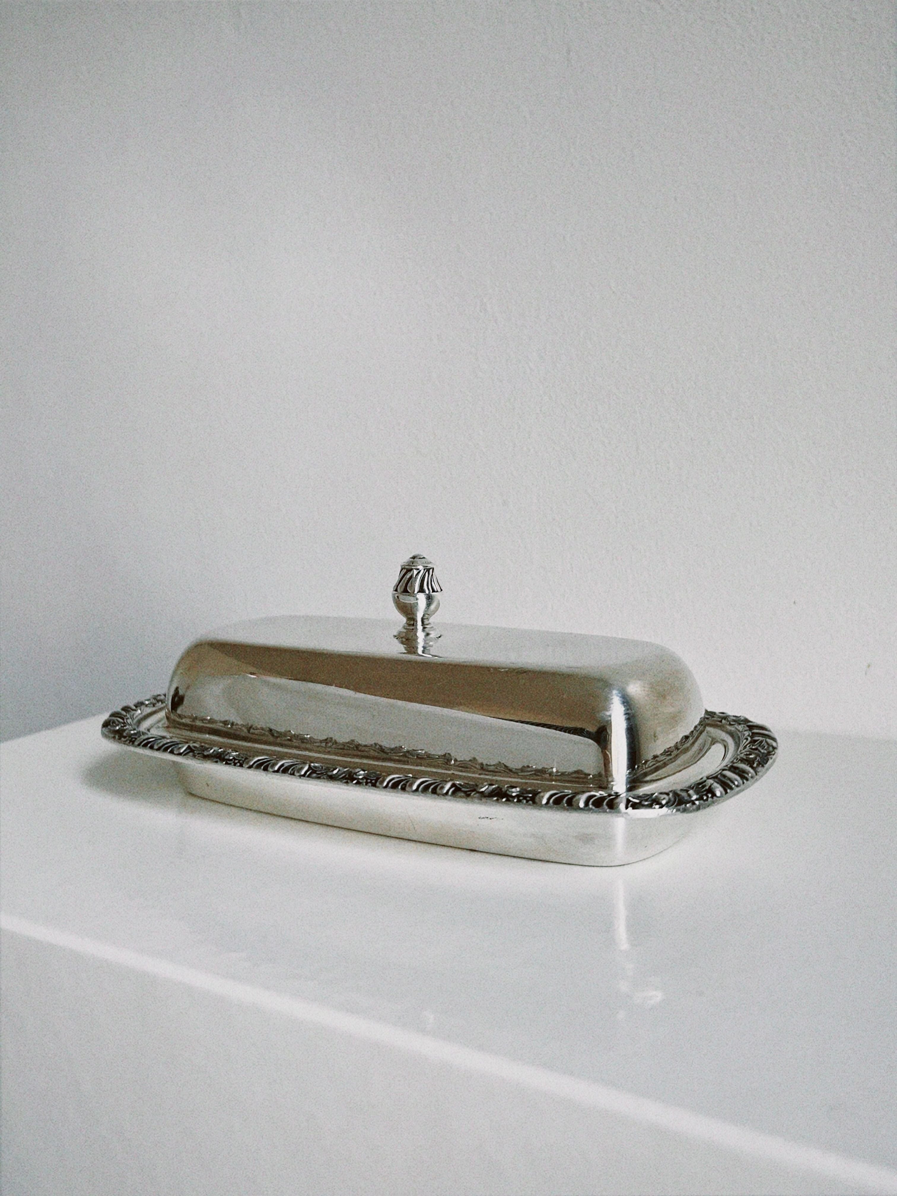 A beautiful silver ornate butter dish with intricate designs and detailing