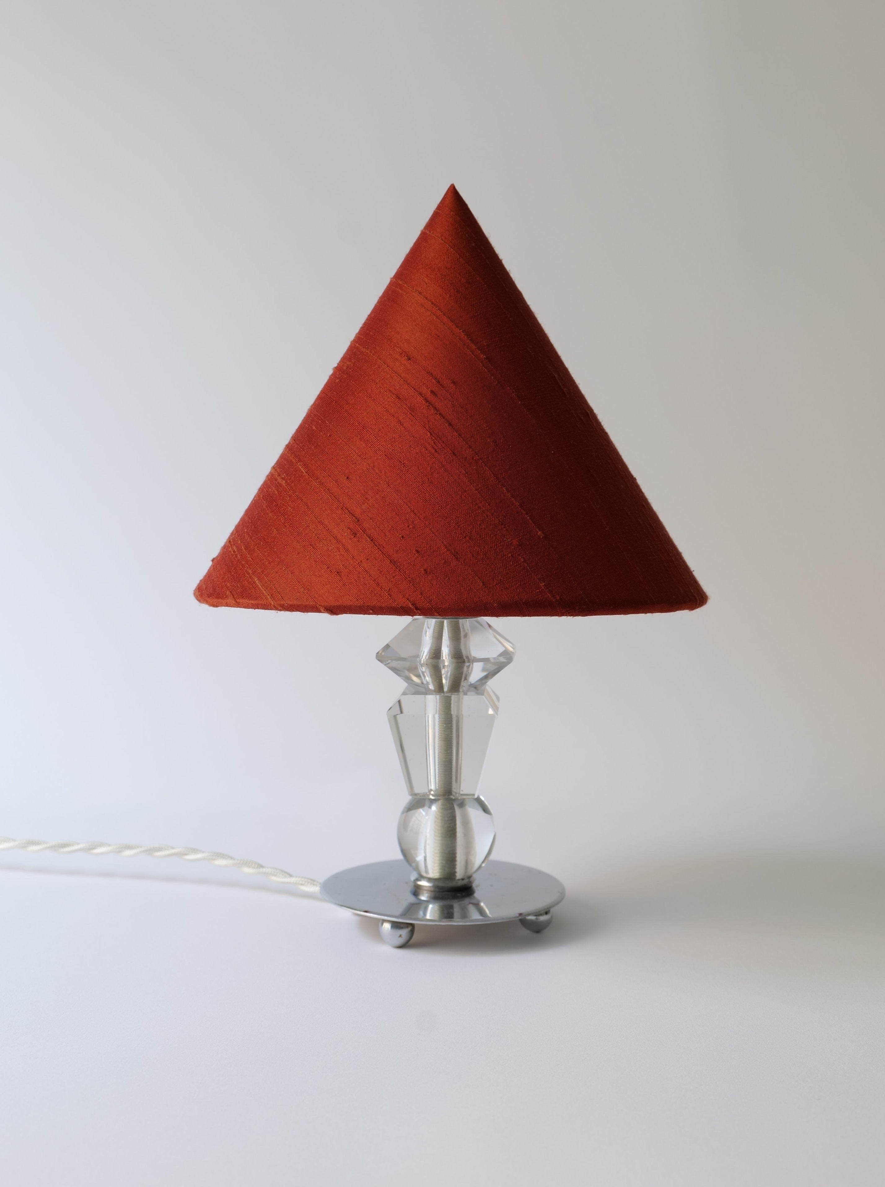 A modern Deco Crystal Table Lamp from Collection Apart with a vivid red conical shade and a sleek, chrome geometric base, set against a plain white background.