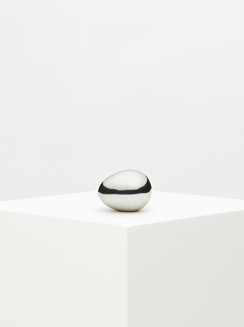 Silver egg paperweight on a marble surface with intricate design details