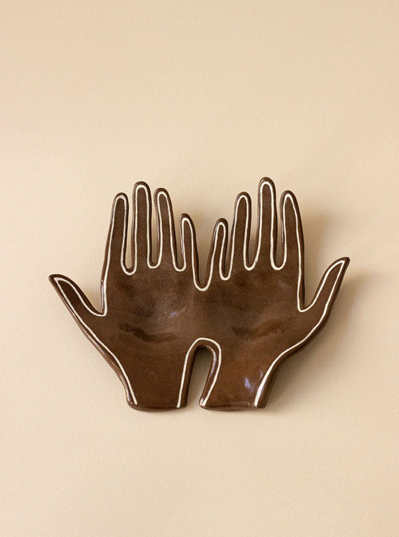 The Main Double "The Line" sculpture by Main Edition features two open hands with fingers pointing upwards, crafted from glossy brown material with white outlines, set against a beige background. Perfect for adding luxury to any interior space.