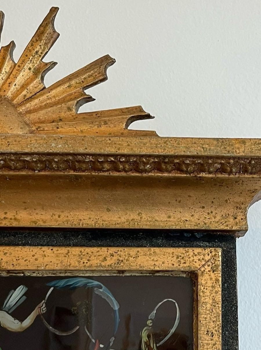 Close-up of a vintage Médecine antique gilded mirror with intricate textures and a distressed golden finish. The top edge features a decorative, leaf-like design with visible chipping, emphasizing its antique appearance and showcasing Swedish craftsmanship.