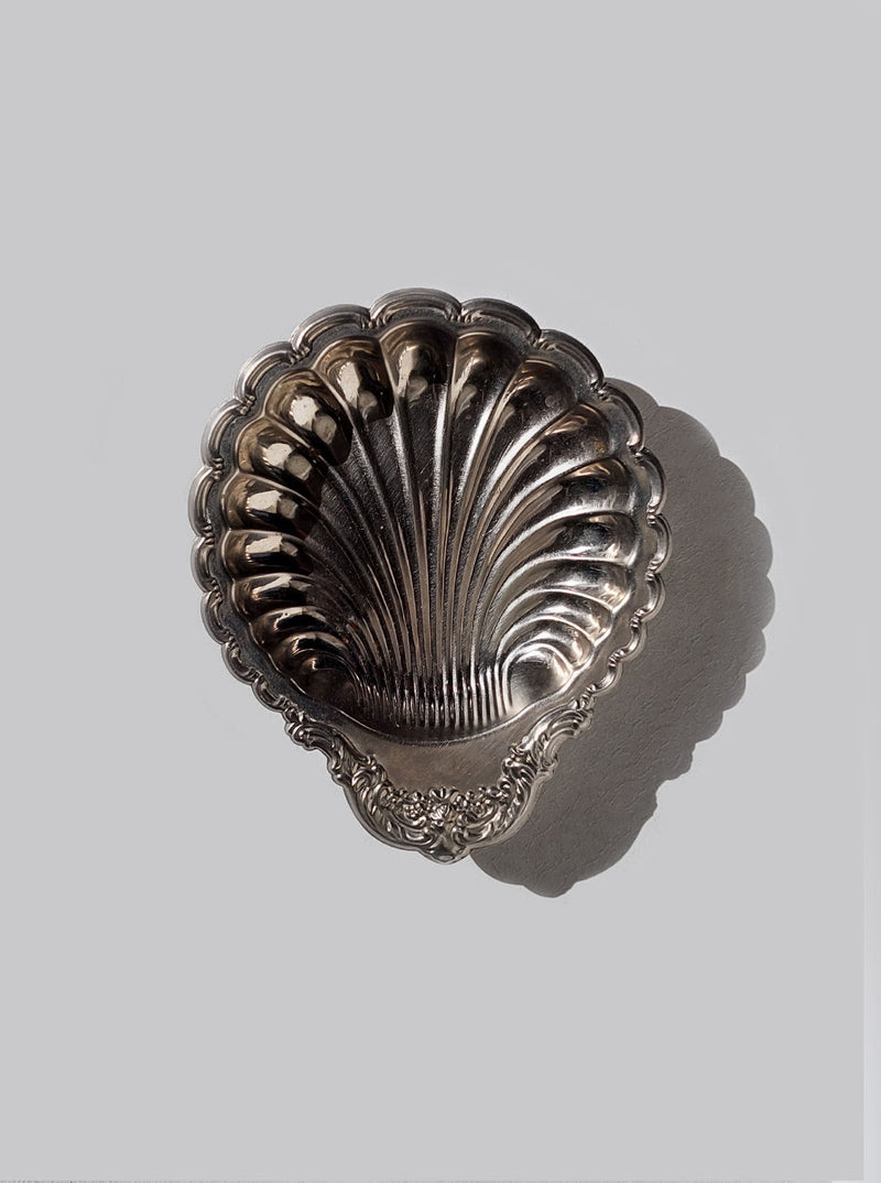 A beautiful shell shaped vide poche made of ceramic in blue and white tones, perfect for storing small items on a desk or table