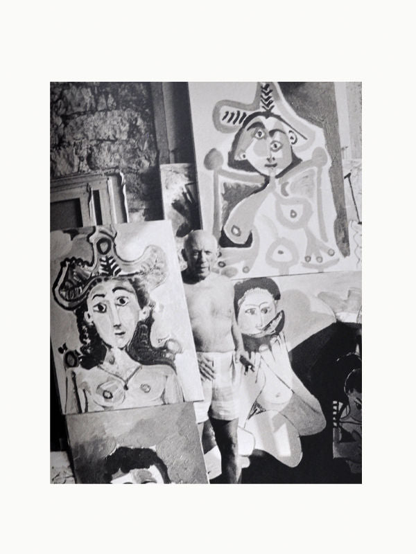 Black and white photo of several expressive paintings and a sculpture in an artist's studio, featuring stylized portraits with abstract and Picasso/Clergue influences by Maison Plage.